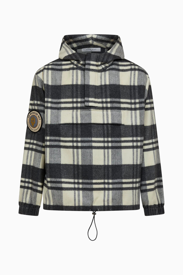 IH NOM UH NIT FW26 cream, grey and black checked anorak with hood, monogram sleeve patch and adjustable drawstring hem, front view.