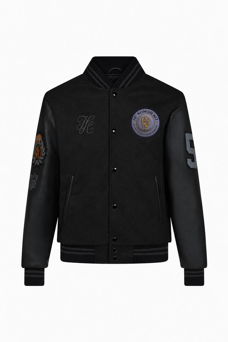 IH NOM UH NIT FW26 black Patch Varsity Jacket with leather sleeves, embroidered patches and number appliqué, front view